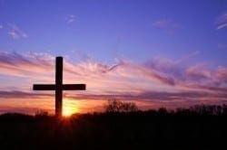 Silhouette of a cross against a vibrant sunrise sky, symbolizing the Love of the King.